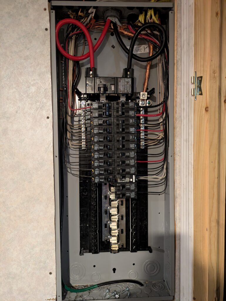 A hand flipping a switch on an electrical fuse box. The box is white and mounted on a wall.